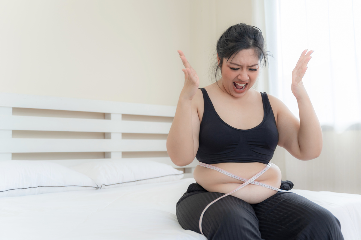 asian fat women , Fat girl , Chubby, overweight unhappy measuring her waist in the bedroom - Woman diet lifestyle overweight problem concept